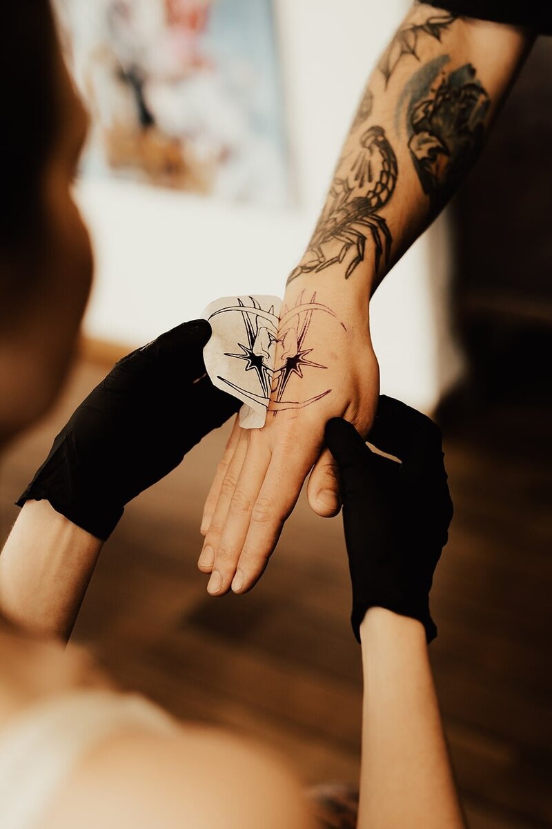 Tatuerare tar av stencil på ovansida hand av en måne och stjärna.