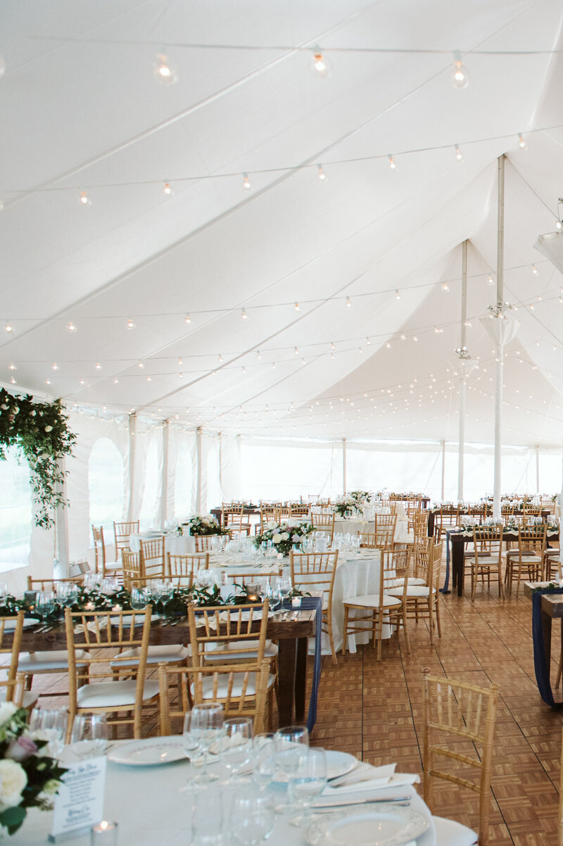 wedding reception with greenery and blue runners in white tent with parquet floor at Cornman Farms in Michigan