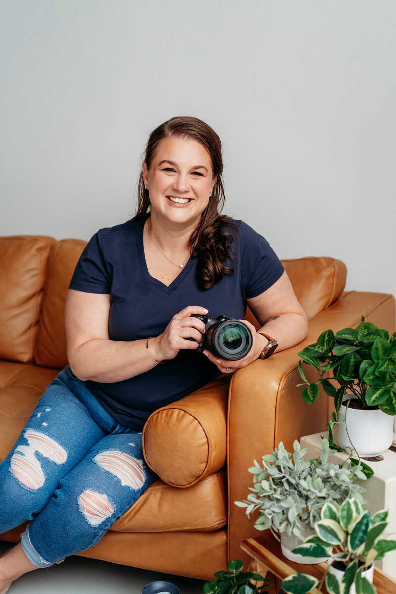Woman posed sitting on a couch holding a cam