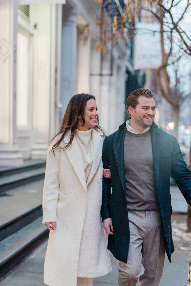 Couples walks down a sidwalk in Soho and smills into the street