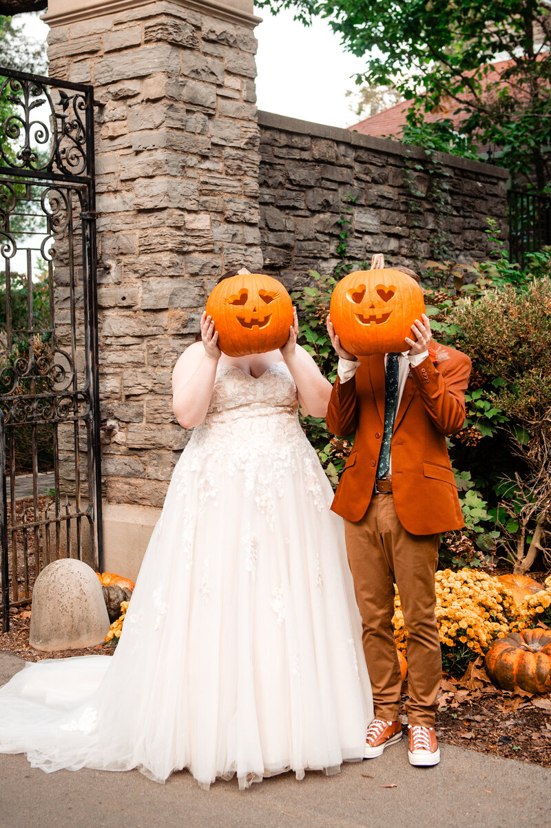 Bride and Groom holding up pumpkin carved during photos