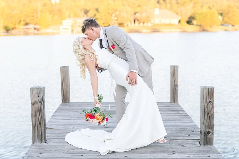 Bride and groom dip kiss on wooden pier | New Water Farms Wedding Photography