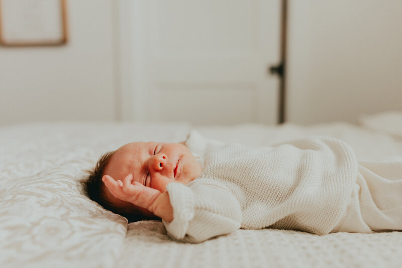 Photo of a newborn baby laying on the master bed with it's eyes closed taken by a langley photographer