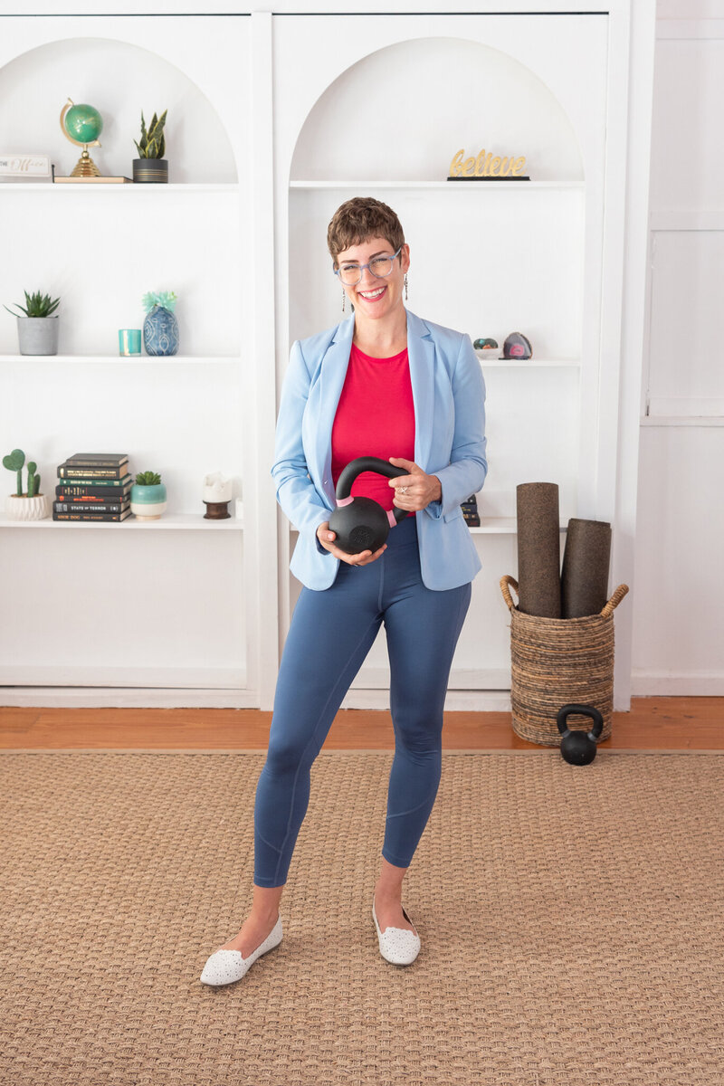 A woman in yoga attire holding a dumbbell.