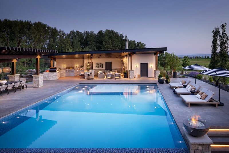 A large outdoor pool with a poolhouse and oversized pool loungers. 