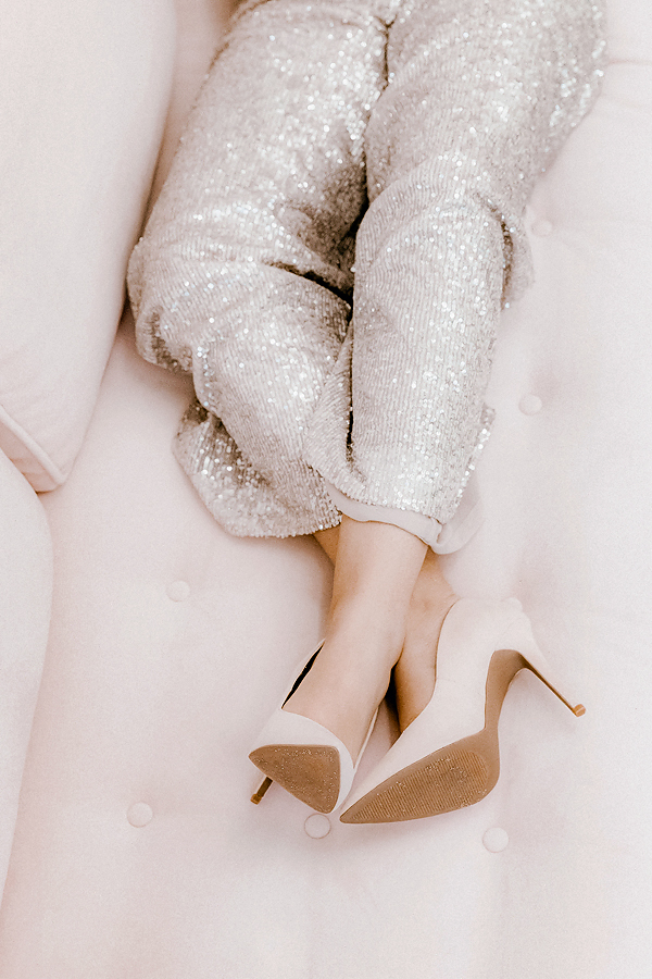 Woman’s legs with shiny pants and heels on a couch