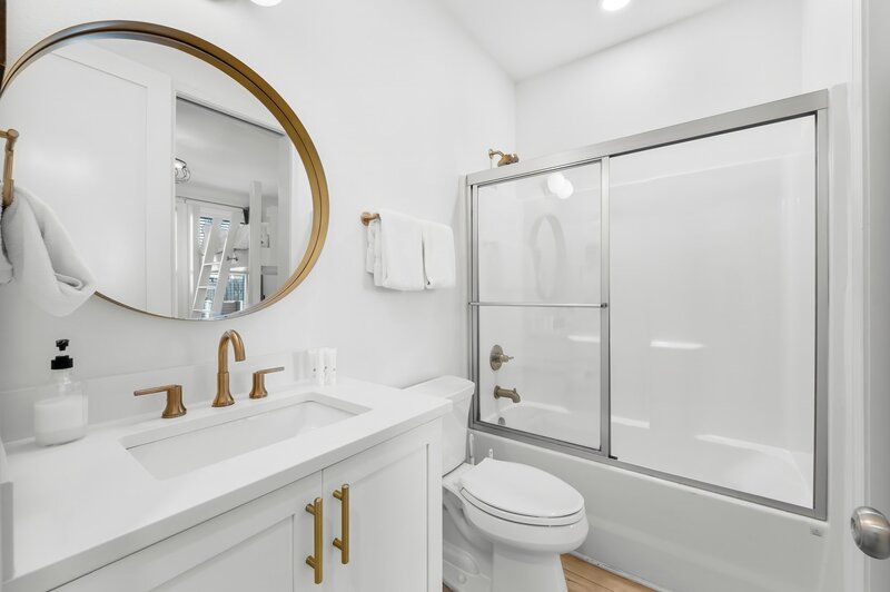 Bathroom with modern white vanity, gold fixtures and full tub at Groovy Shack, ideal for groups staying near Destin and Carillon Beach