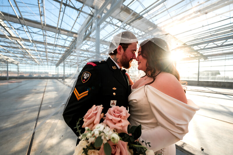 bride and groom facing each other in a green house with sunset behind them at the St. Albert Enjoy Centre