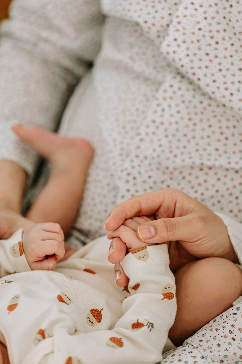 Mom holding newborn baby's hand 