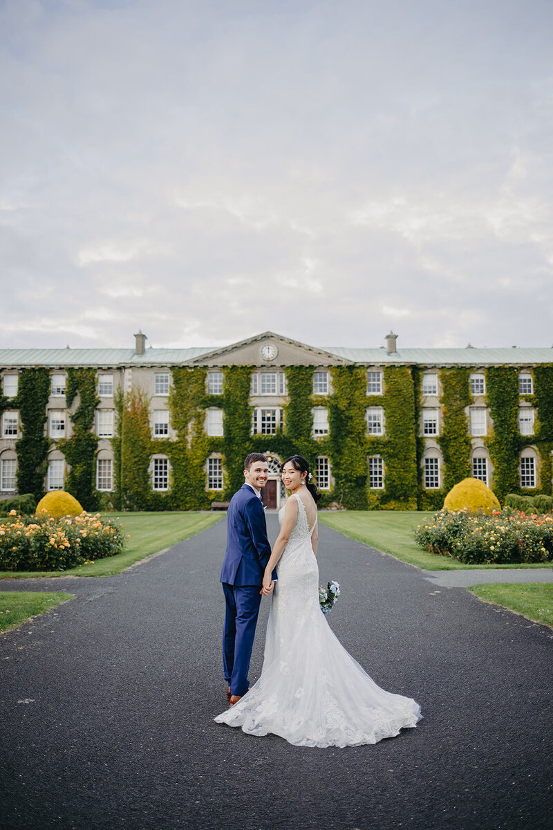Bride and groom sharing a quiet moment in the courtyard of Maynooth University, with its historic buildings as a romantic backdrop.