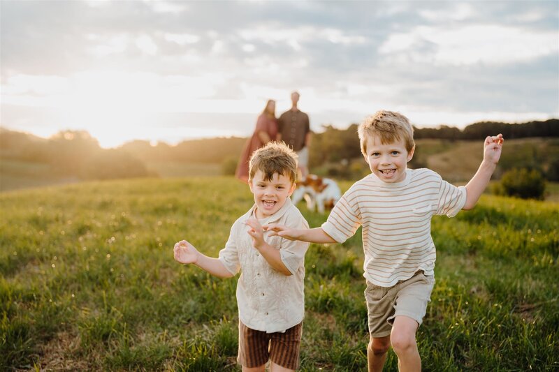 Holly & Jesses two little boys running through a field laughing during their family photoshoot in waikato with photographer haley adele