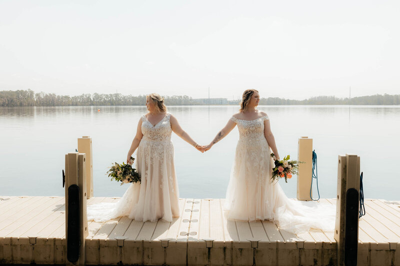 Orlando Florida Brides hold hands on a dock while looking away