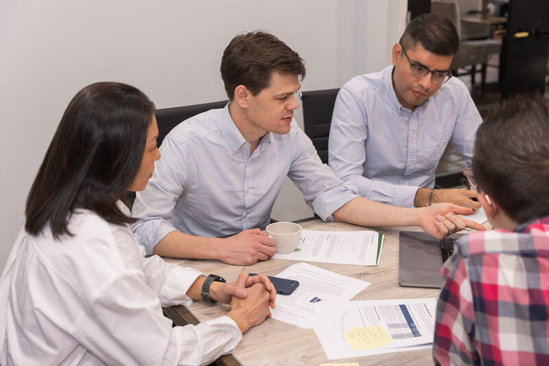 man leading a meeting with other people pointing at his computer in an Atlanta GA conference room Brand Photographer