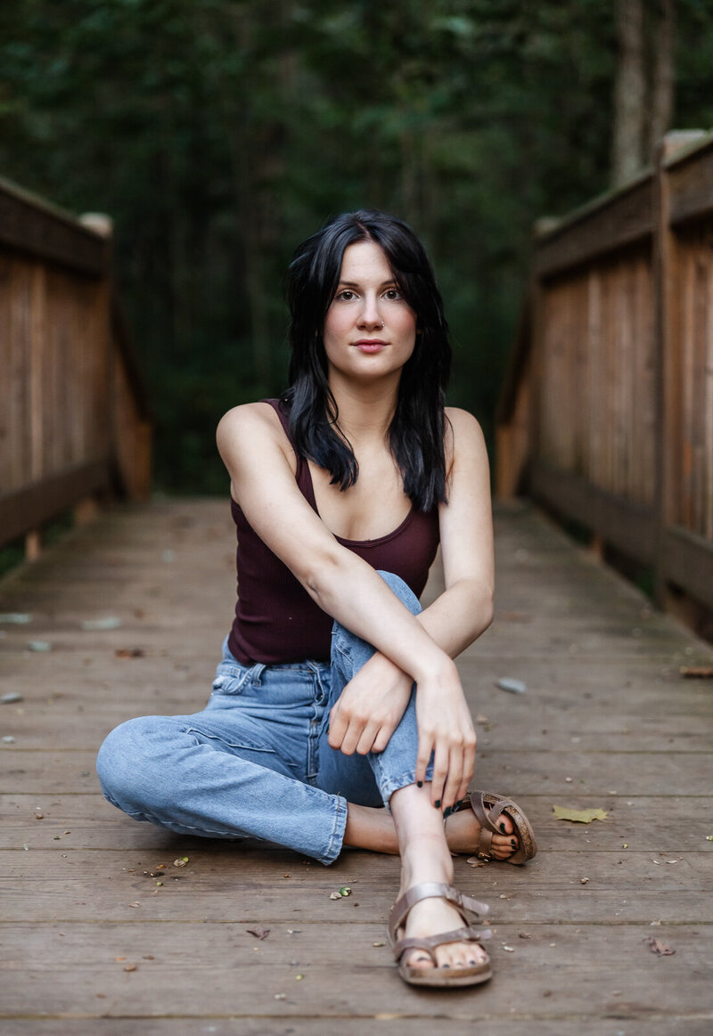 Senior girl sitting on wooden walking bridge. 
