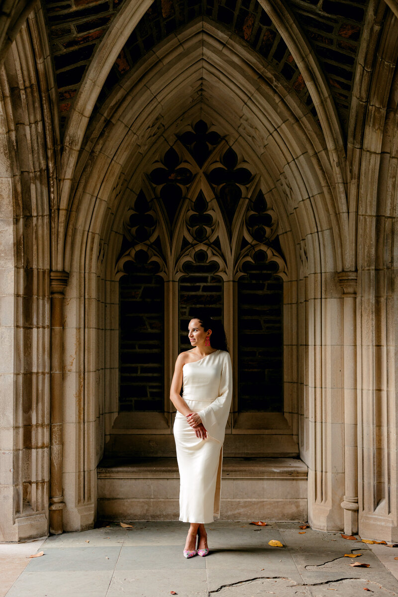 Graduate wearing white dress and pink floral heels with pink statement earrings.