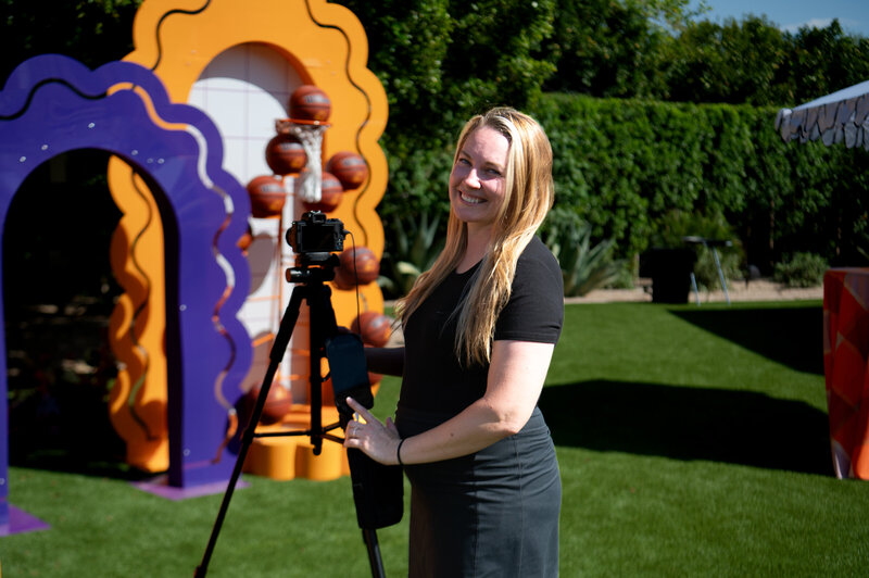 MISGIF event photographer smiling with camera and tripod at a corporate event in Phoenix, Arizona, showcasing professional photo coverage for branded outdoor experiences.