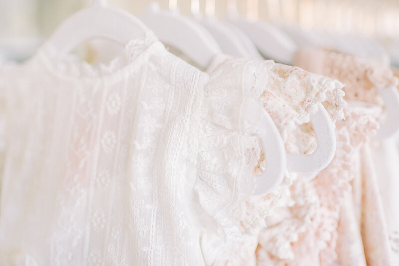 A white lace dress from Noralee is on a display rack for a milestone client to use during their photography session