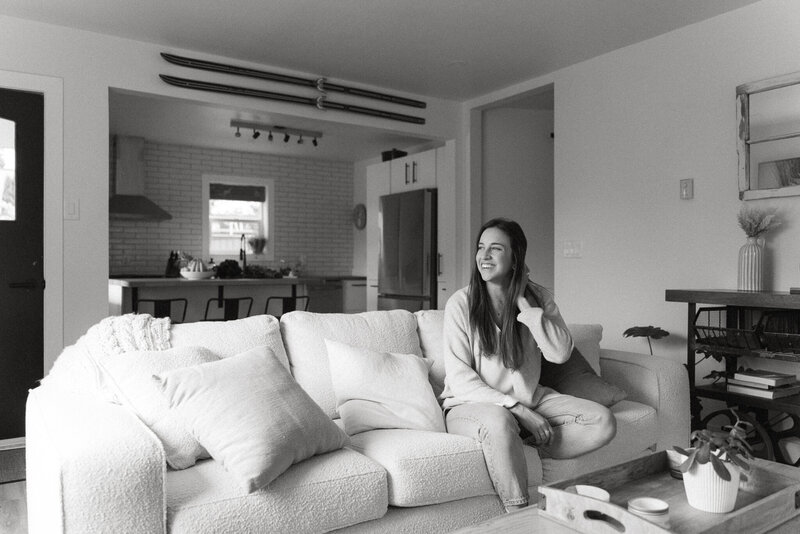 Woman with brown hair and a tan sweater seasoning food in the kitchen