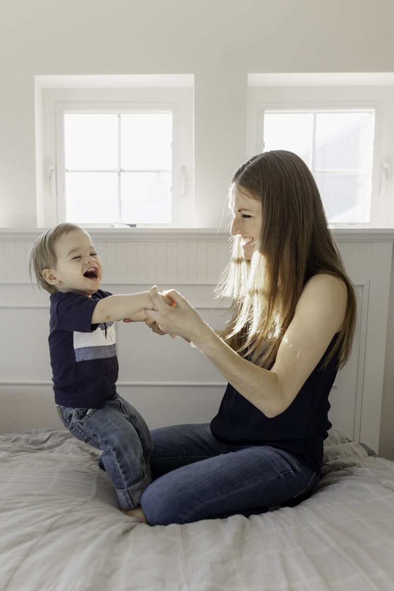 Liz and Ollie laughing while jumping on the bed