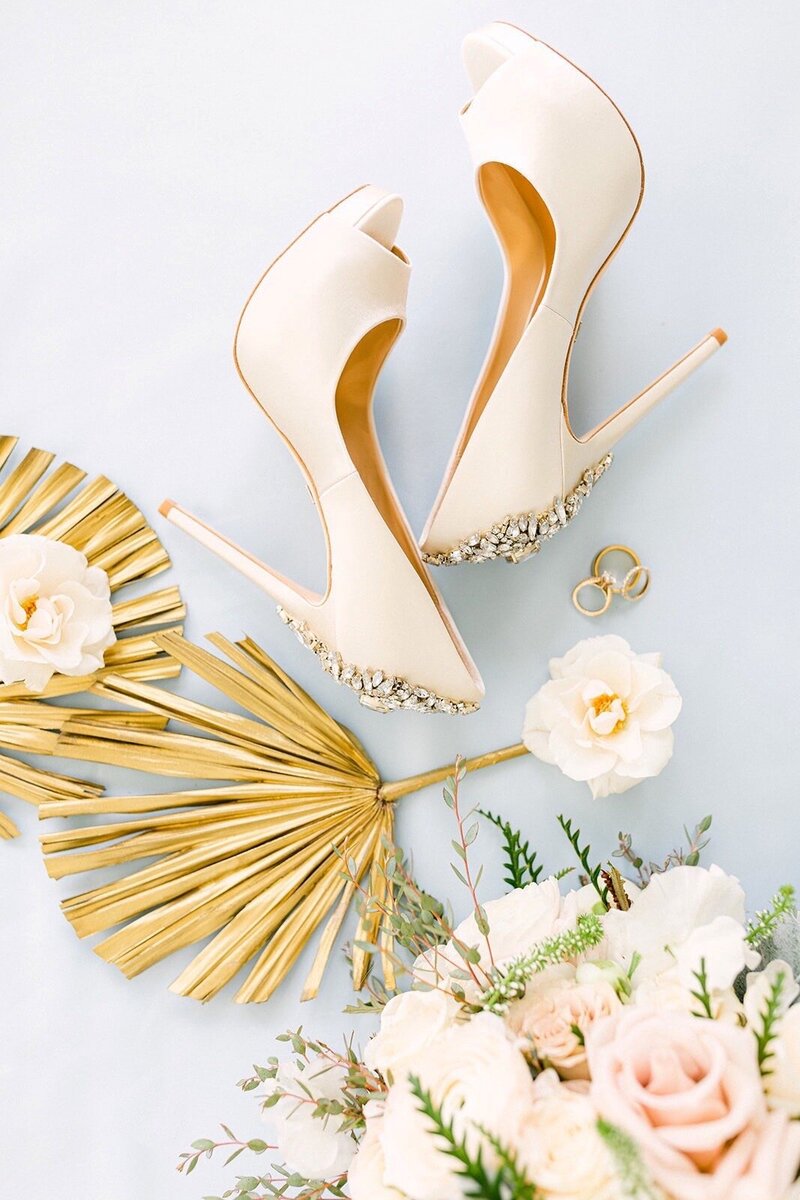 Flat lay photo of rings, shoes, and flowers