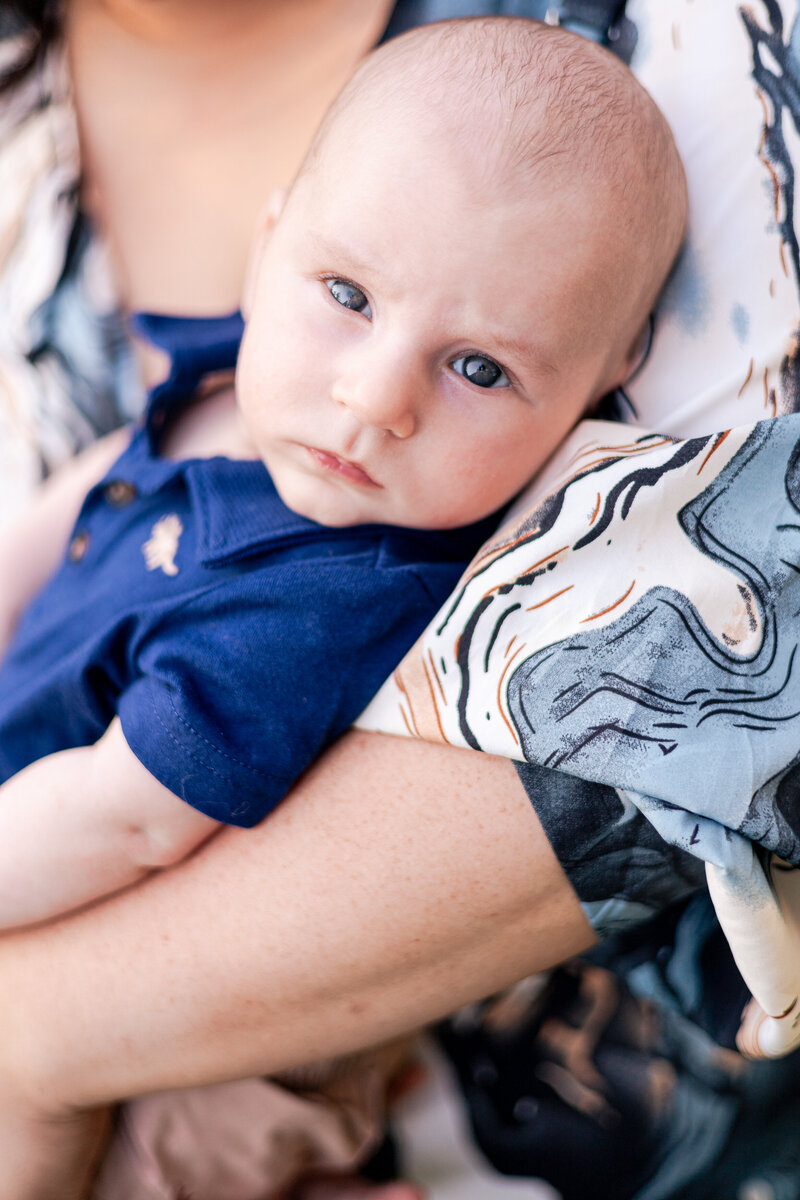 Baby in mother's arms looking at the camera.