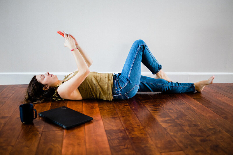 Photo of Andrea Shah lying down the floor holding her phone