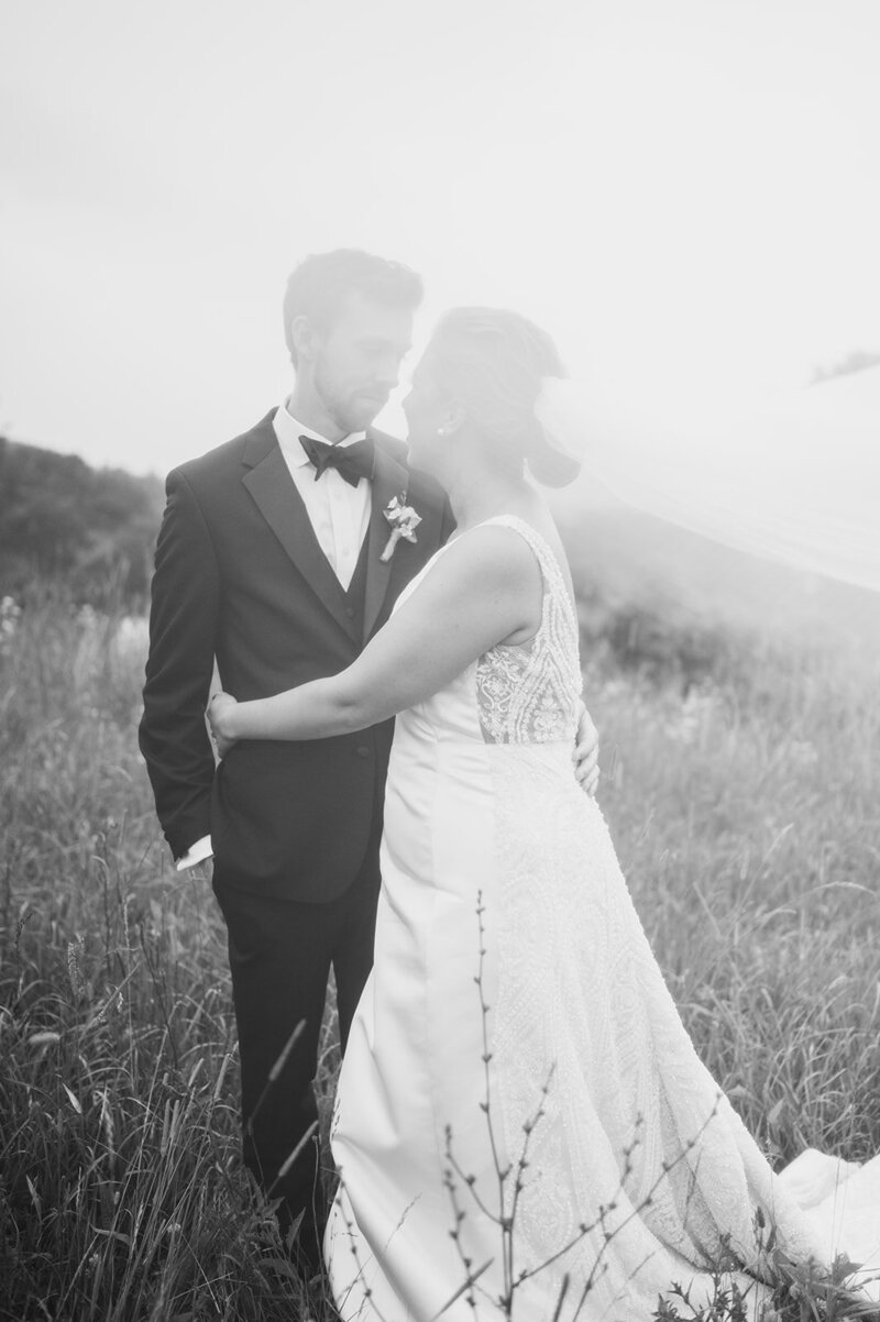 bride and groom kiss in open field in the adirondacks