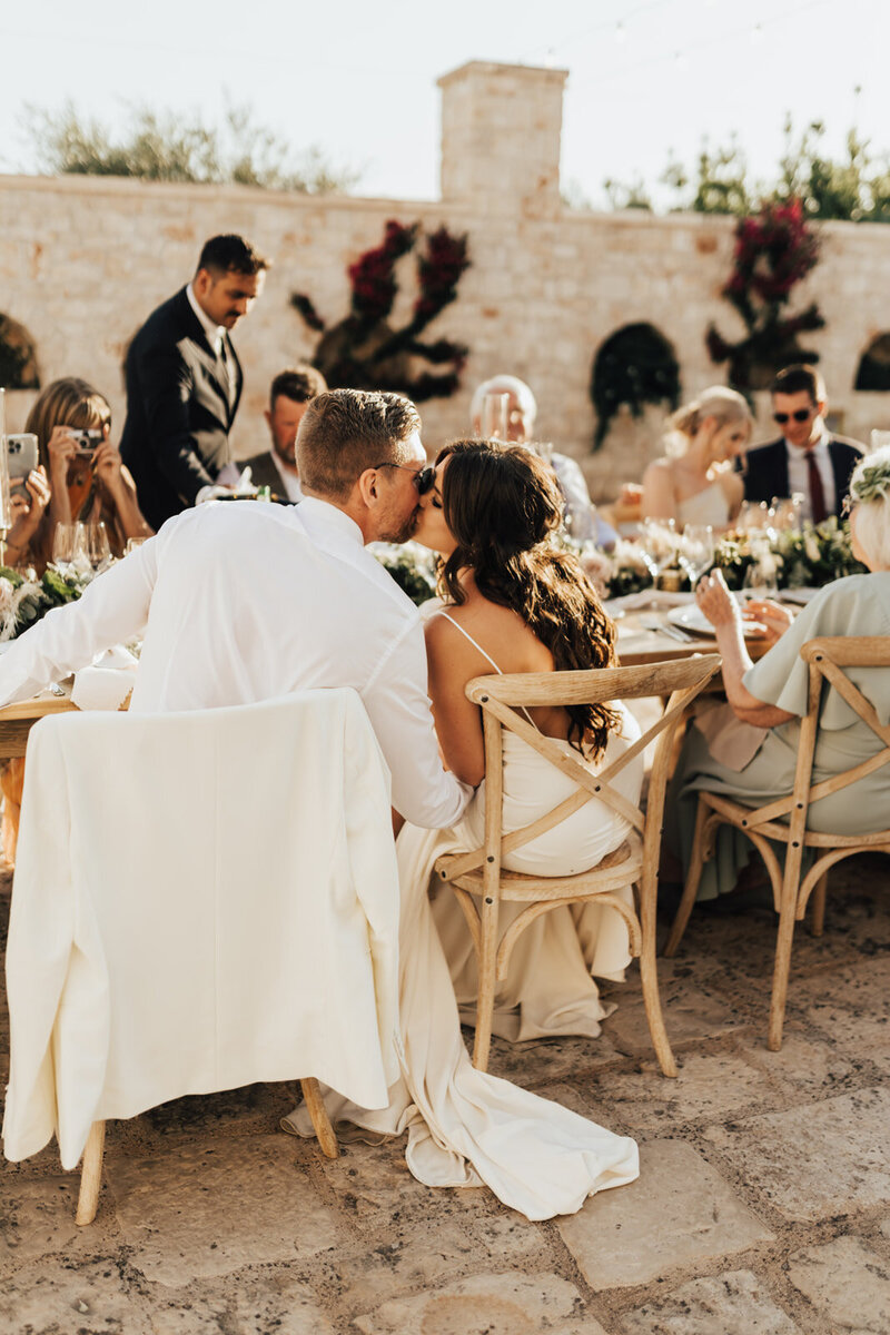 bride and groom kissing at table at wedding