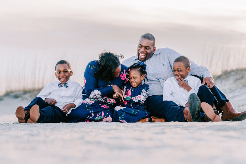 Family sitting on the sand laughing at Palmetto Dunes in Hilton Head, SC. Family photographers Savannah, GA.