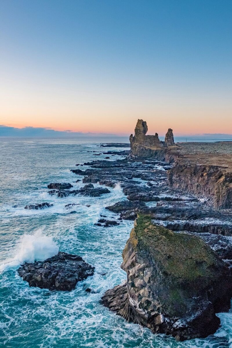 Prise de vue sur une falaise en bord de mer avec un coucher de soleil à l'horizon