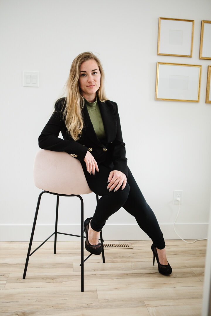 Realtor Tamara sitting in a soft pink chair in a pristine white home