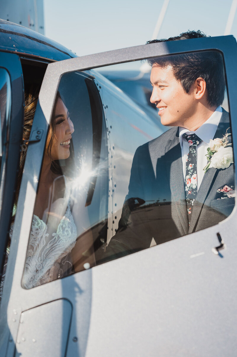 17-radiant-love-events-bride-inside-helicopter-groom-opening-door-peering-through-clear-door-window-romantic-elegant-timeless