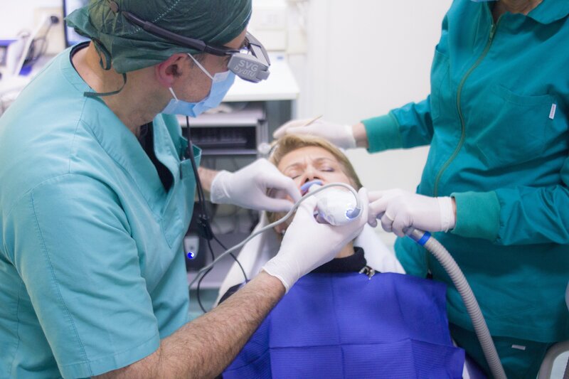 a dentist and assistant work on whitening a patient's smile
