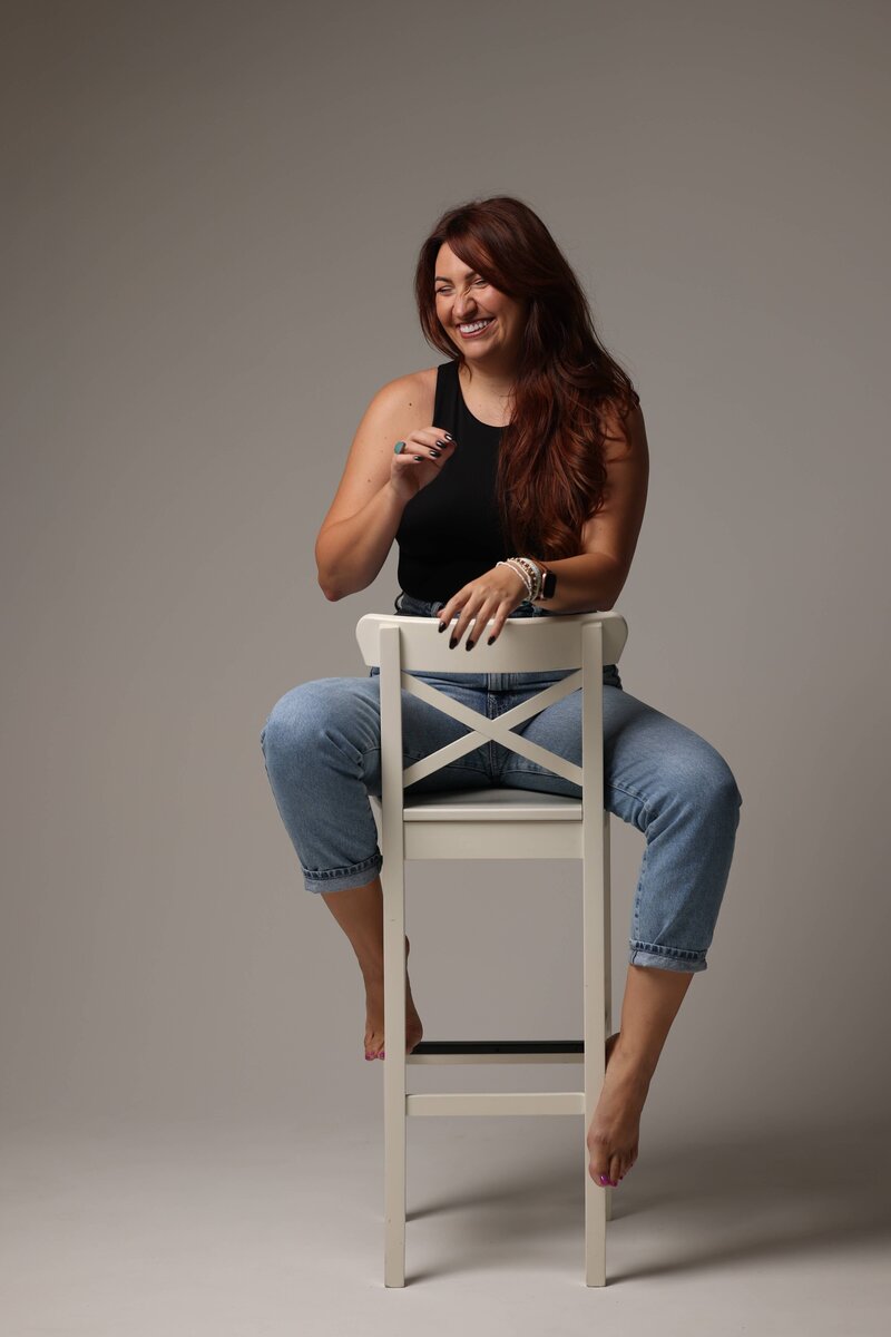 A Showit Website designer sitting on a chair and laughing at the camera