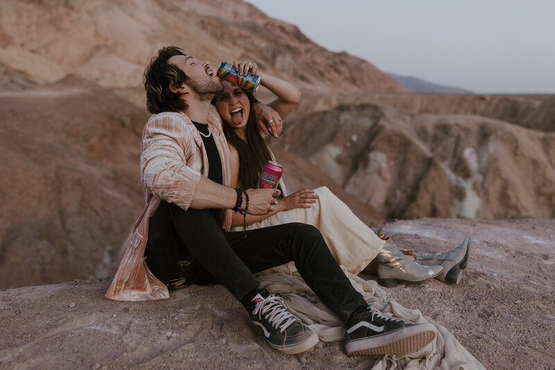 couple laughing while sitting on rock