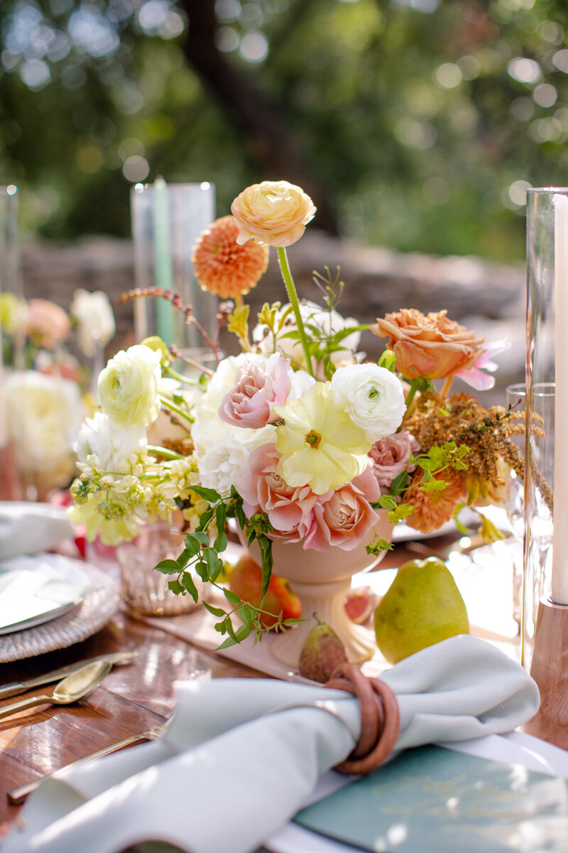 An orange floral centerpiece sits on a wooden table outside