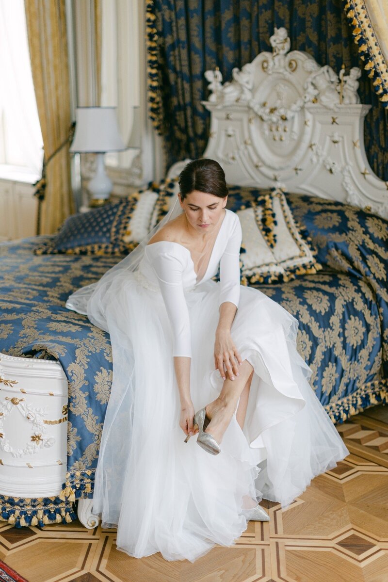 Elegant and luxury bride putting on her bridal shoes in luxury Imperial Hotel in Vienna