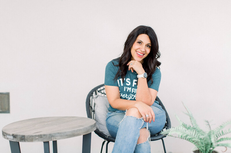 smiling woman sitting with hand on her chin sitting with legs crossed