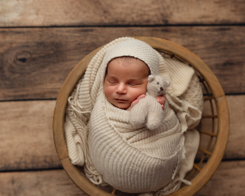 Neutral, cozy newborn portrait with cream wraps and handmade teddy.