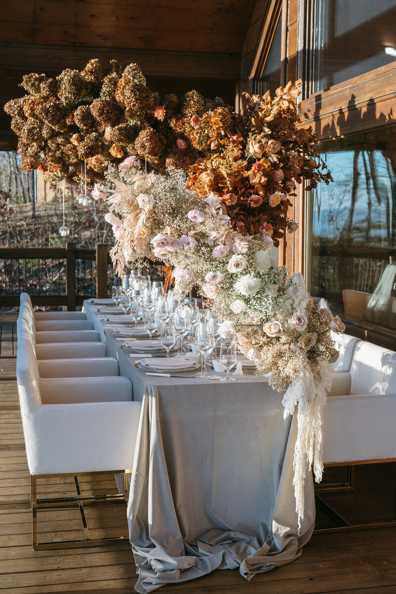 Outdoor wedding reception with dramatic hanging floral installation and neutral-toned table setting