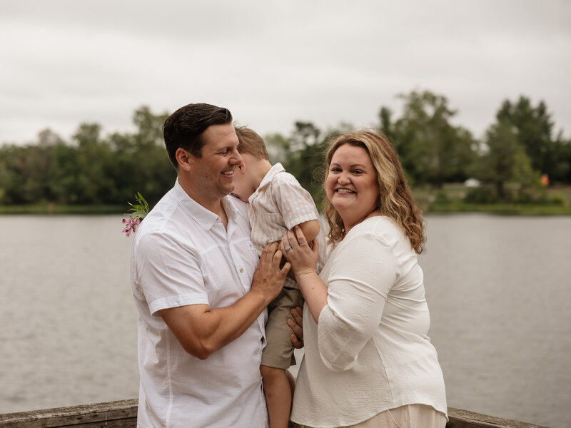 Candid Moment of a young family with their child, laughing smiling, at a lake. 