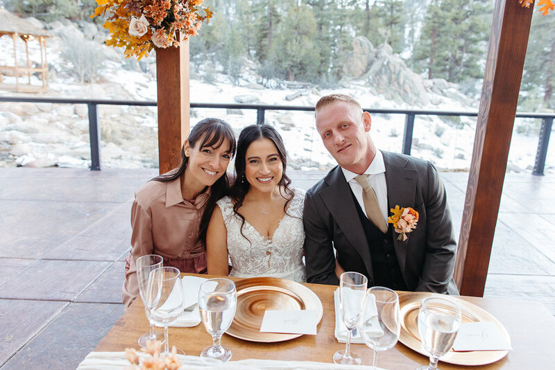 Newlyweds at sweetheart table with coordinator at Cienaga Creek Ranch