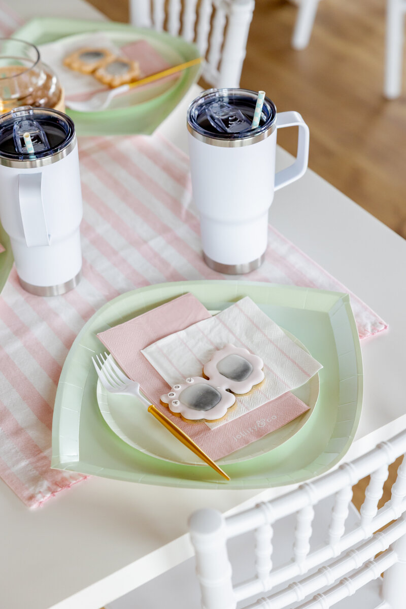 White table and chairs with kids dessert with sunglass cookies and paper goods.