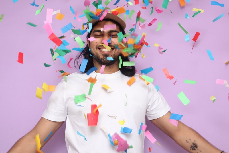 Smiling guest surrounded by colorful confetti in front of a pastel purple backdrop, captured in a high-energy moment by MISGIF’s interactive photo booth for corporate events and brand activations in Phoenix, Arizona