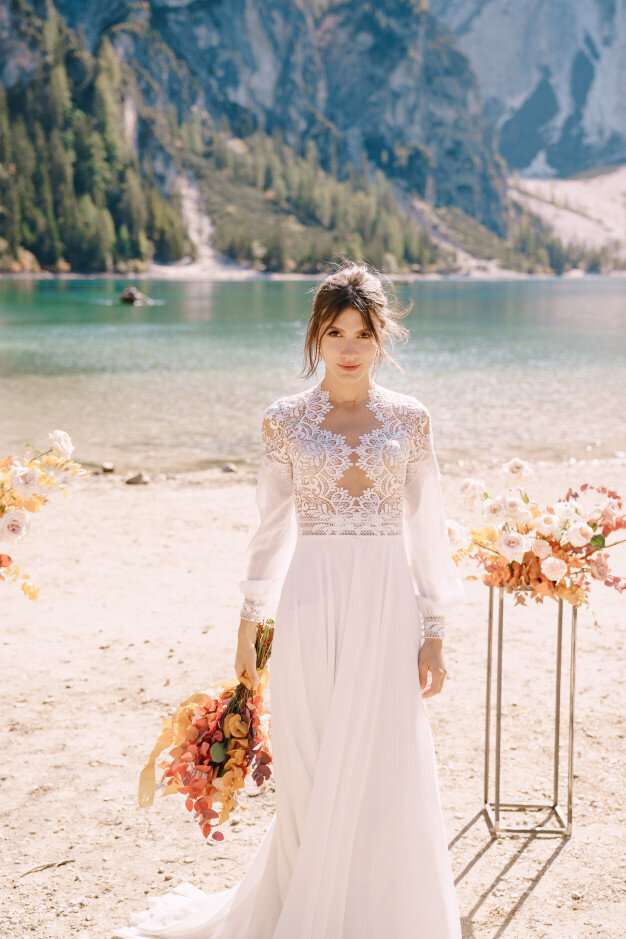 beautiful-bride-white-dress-with-sleeves-lace-with-yellow-autumn-bouquet-posing-lago-di-braies-italy_278455-32