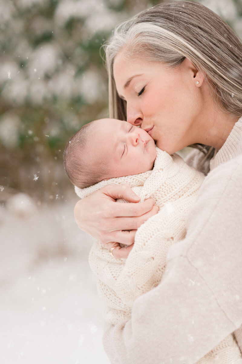 newborn in the snow in mom's arms