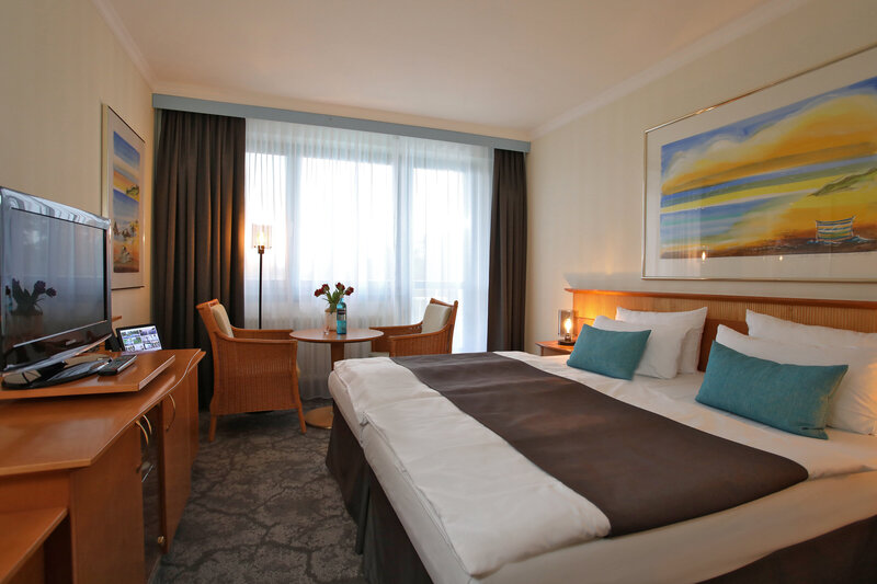 Ansicht des Zimmers mit Doppelbett, TV und Sitzgelegenheit.
