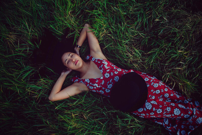 girl laying in tall grass with red dress