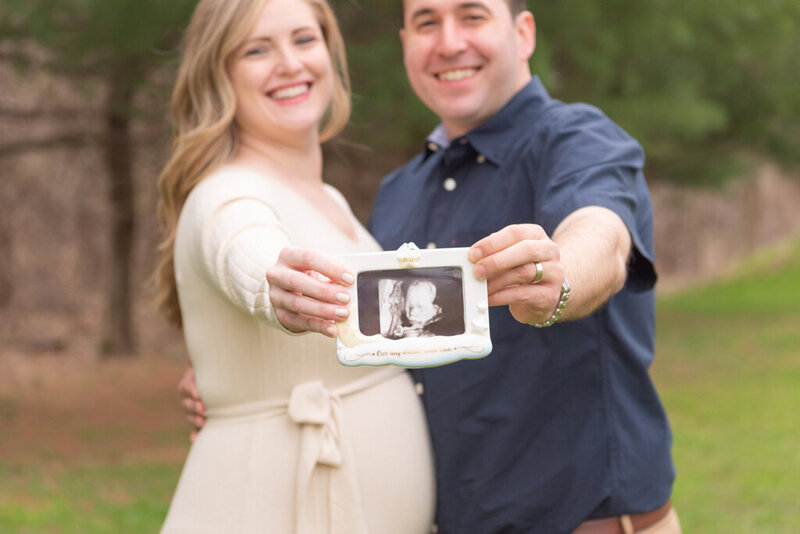A couple holding a sonogram picture and smiling with joy.