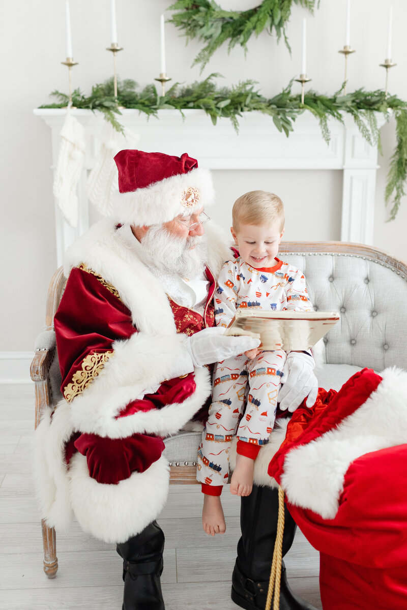 A photo of Santa holding a child on his lap showing him a gift he pulled out of his Santa sack.